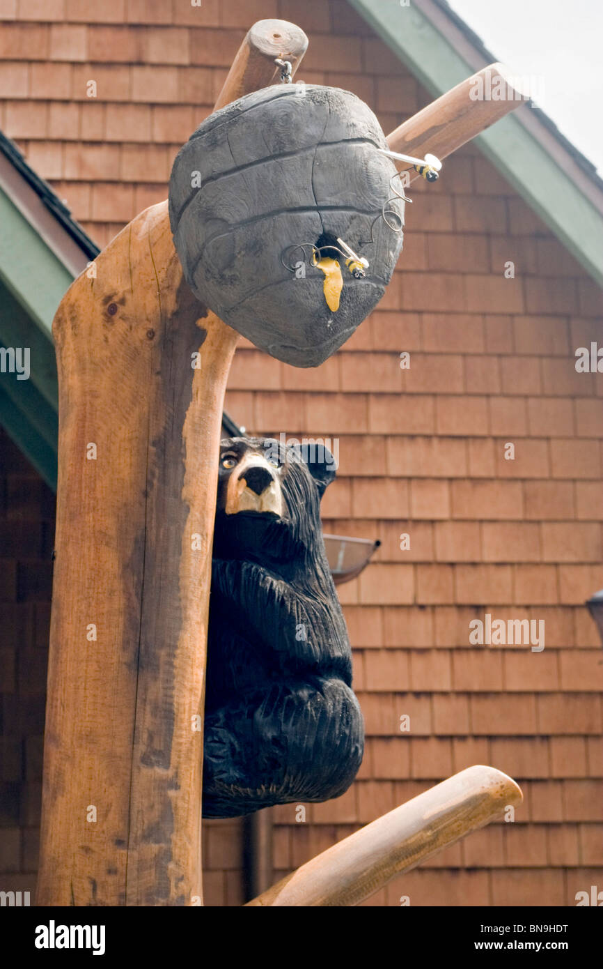 La sculpture sur bois de l'ours et ruche accrochée à l'arbre sculpté en bois Banque D'Images