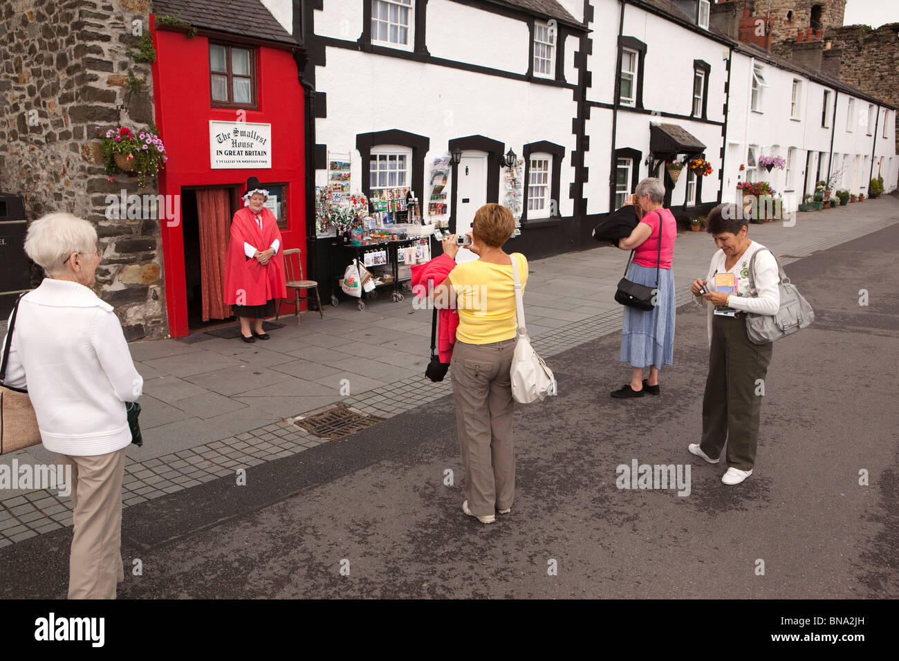 Pays de Galles, Gwynedd, Conway, touristes photographiant femme en costume gallois à l'extérieur de la Grande-Bretagne est plus petite maison Banque D'Images