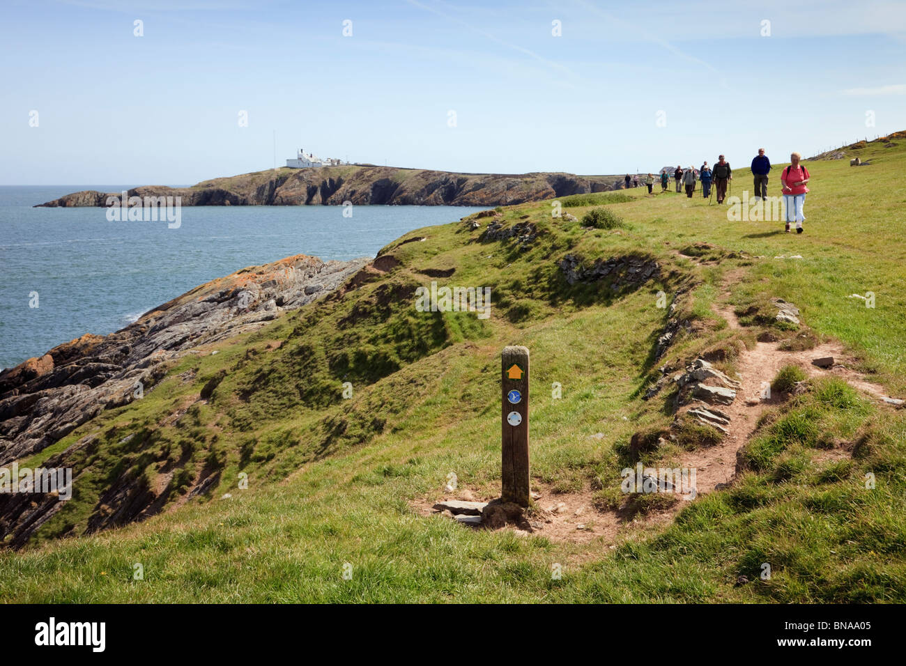 Isle of Anglesey Sentier du littoral et le Pays de Galles côte waymarker avec les gens à pied de Lynas Point. Llaneilian Isle of Anglesey au nord du Pays de Galles UK Banque D'Images