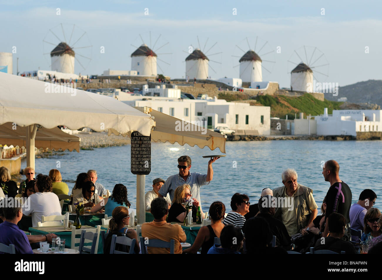 Mykonos. La Grèce. Le Kastro / Little Venice bar en bord de mer et les moulins à vent à l'arrière-plan. Banque D'Images