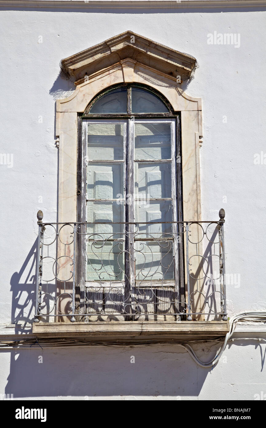 Rustique brun fenêtre avec un balcon en fer forgé sur un mur de plâtre blanc Banque D'Images