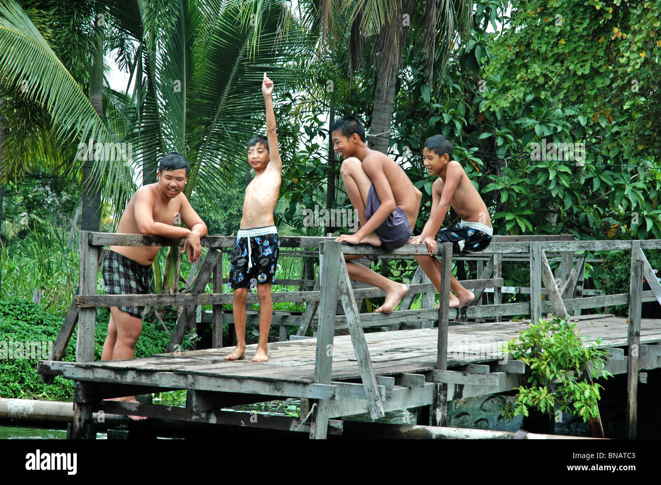 Quatre garçons à leur canal préféré natation place vague pour les bateaux de passage, Banque D'Images