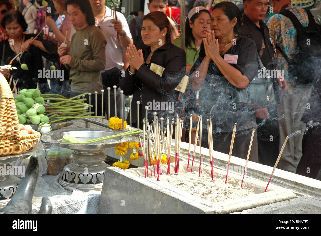 Les femmes allument des bougies et prier à un temple à Bangkok en Thaïlande Banque D'Images