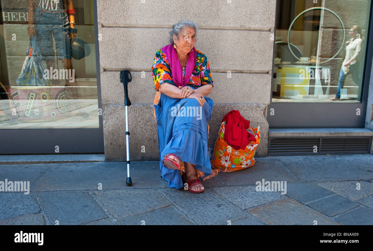 Personnes âgées gypsy femme assise à l'extérieur d'une boutique de luxe en centre ville Banque D'Images