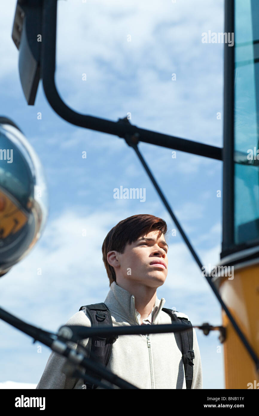 Homme high school student standing outside school bus Banque D'Images
