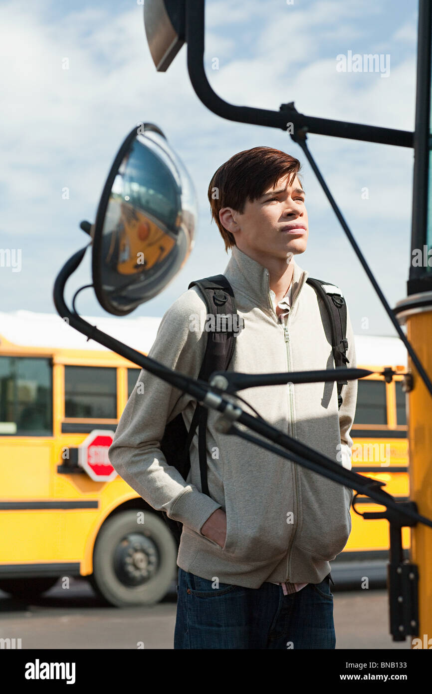 Homme high school student standing outside school bus Banque D'Images