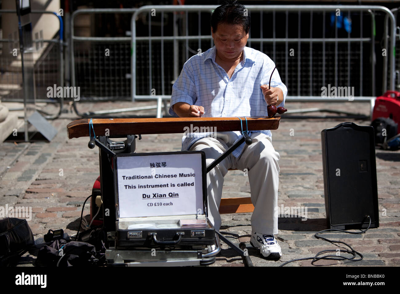 Street bucker jouant un instrument de musique chinois appelé duxianqin ou du xian qin, Covent Garden, Londres, Angleterre, Royaume-Uni. Banque D'Images