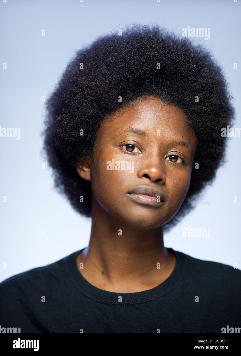 Close-up portrait de jeune femme noire avec un afro dans un t-shirt à regarder camera Banque D'Images