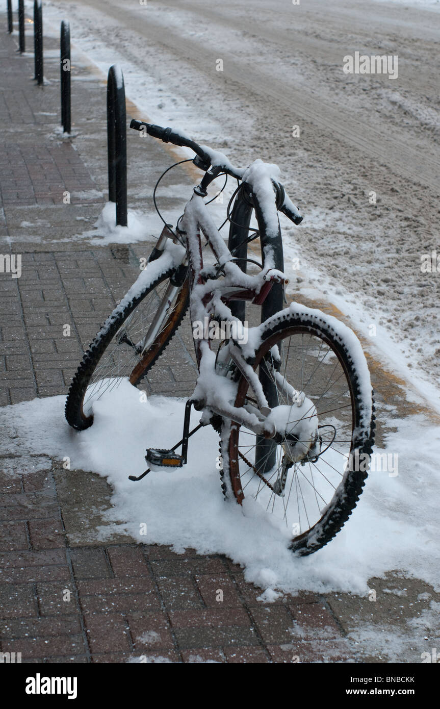 La neige a couvert une bicyclette est enchaîné à un poteau près de la route dans la région de West Lafayette, Indiana Banque D'Images