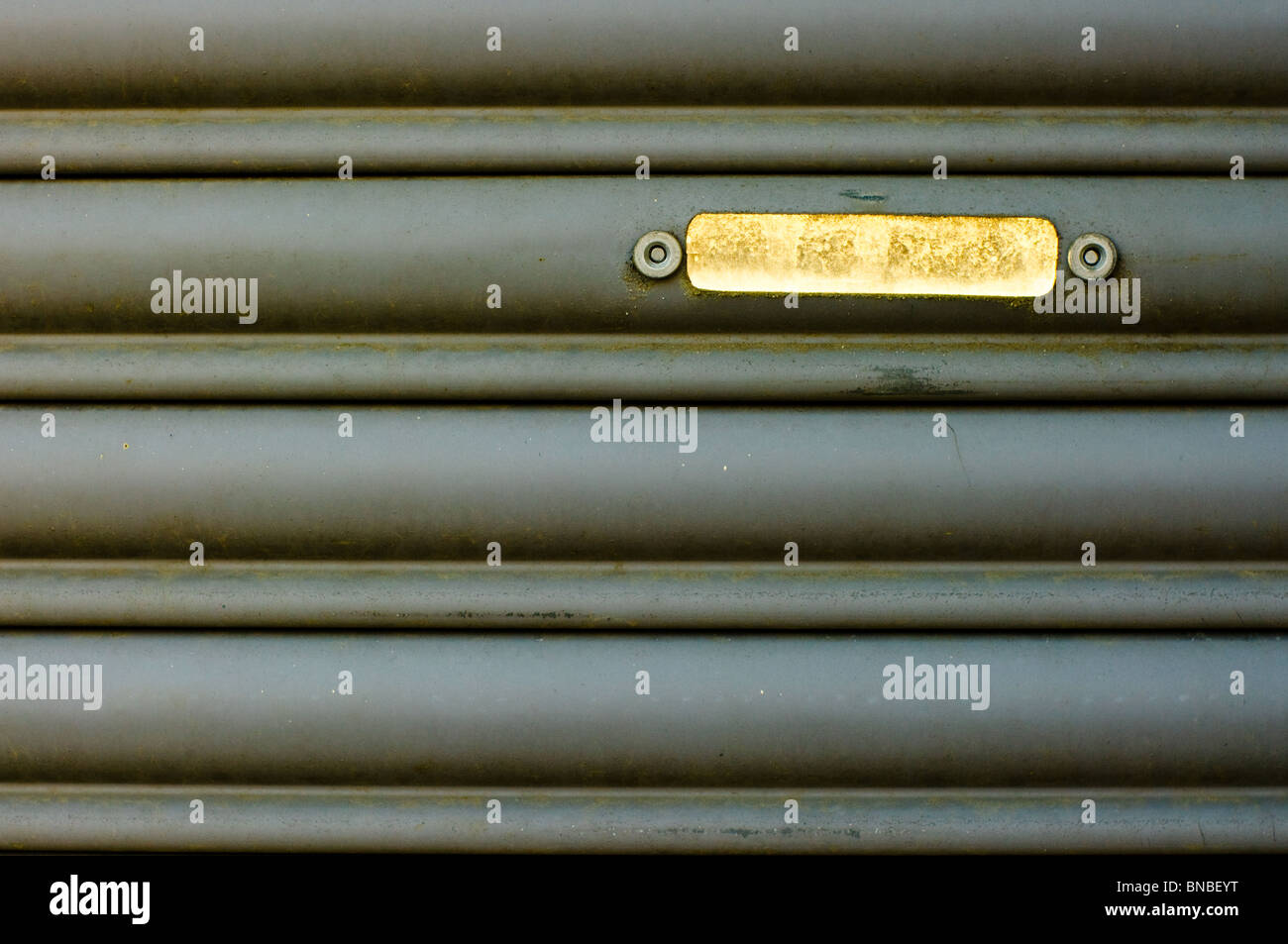 Une petite fenêtre illuminée se détache sur une ancienne porte de garage. Banque D'Images