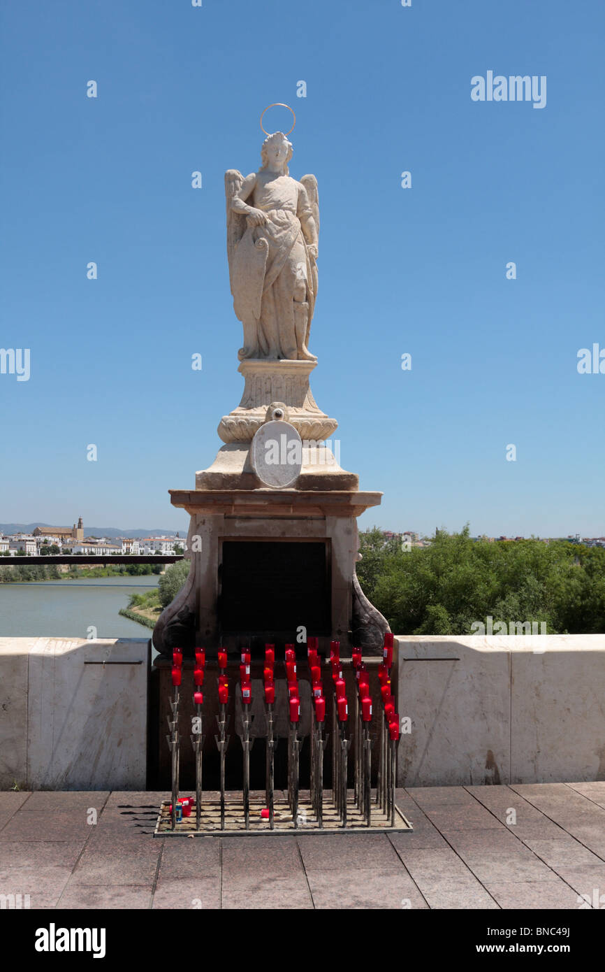 Une statue d'un ange sur le pont Puente Romano avec bougies votives devant Cordoba Andalousie Espagne Europe Banque D'Images