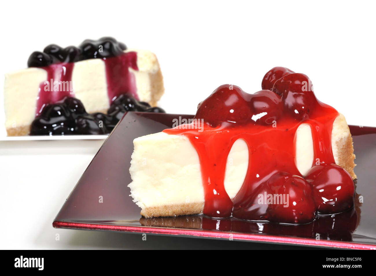 Tranches de gâteau au fromage aux fraises et bleuets isolé sur fond blanc. Banque D'Images