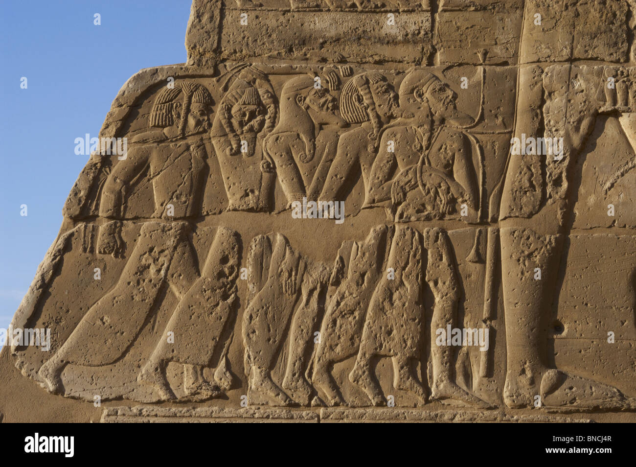 Temple de Ramsès III. Relief représentant des prisonniers de guerre, aux pieds du pharaon, représenté une plus grande taille. Banque D'Images
