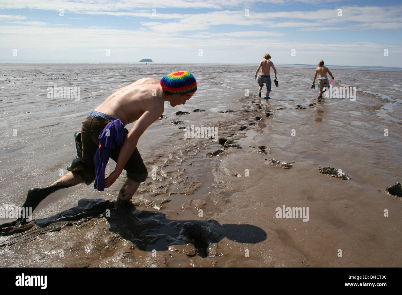 Groupe de jeunes marchant lourdement dans la boue durant la marée basse, Weston-Super-Mare, UK Banque D'Images