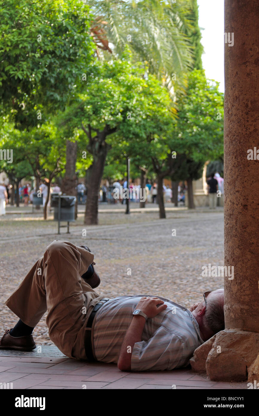 L'homme de prendre une sieste en fin d'après-midi dans la cour de la cathédrale de Cordoba Andalousie Espagne Europe Banque D'Images