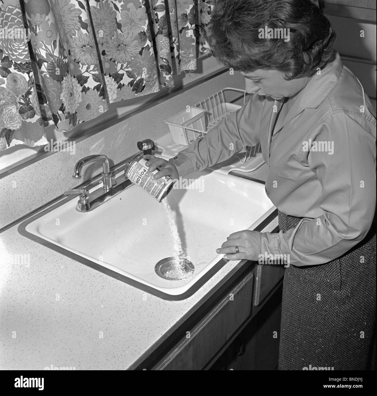 High angle view of a young woman pouring nettoyant pour tuyaux dans un évier Banque D'Images