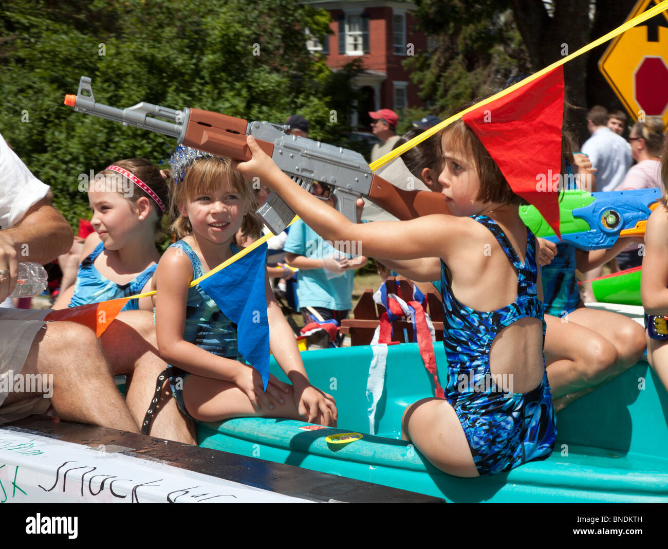 Amherst, New Hampshire - une fille équitation dans un flotteur dans la parade du 4 juillet utilise un canon à eau pour pulvériser les spectateurs. Banque D'Images