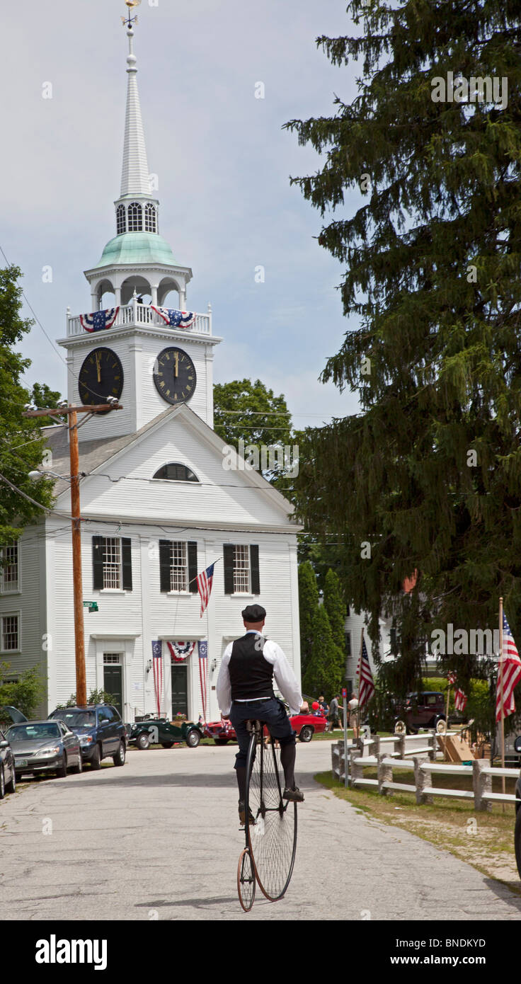 Un homme d'une des tours de roue haute antique location près d'une église de la congrégation à la suite d'une parade le 4 juillet Banque D'Images