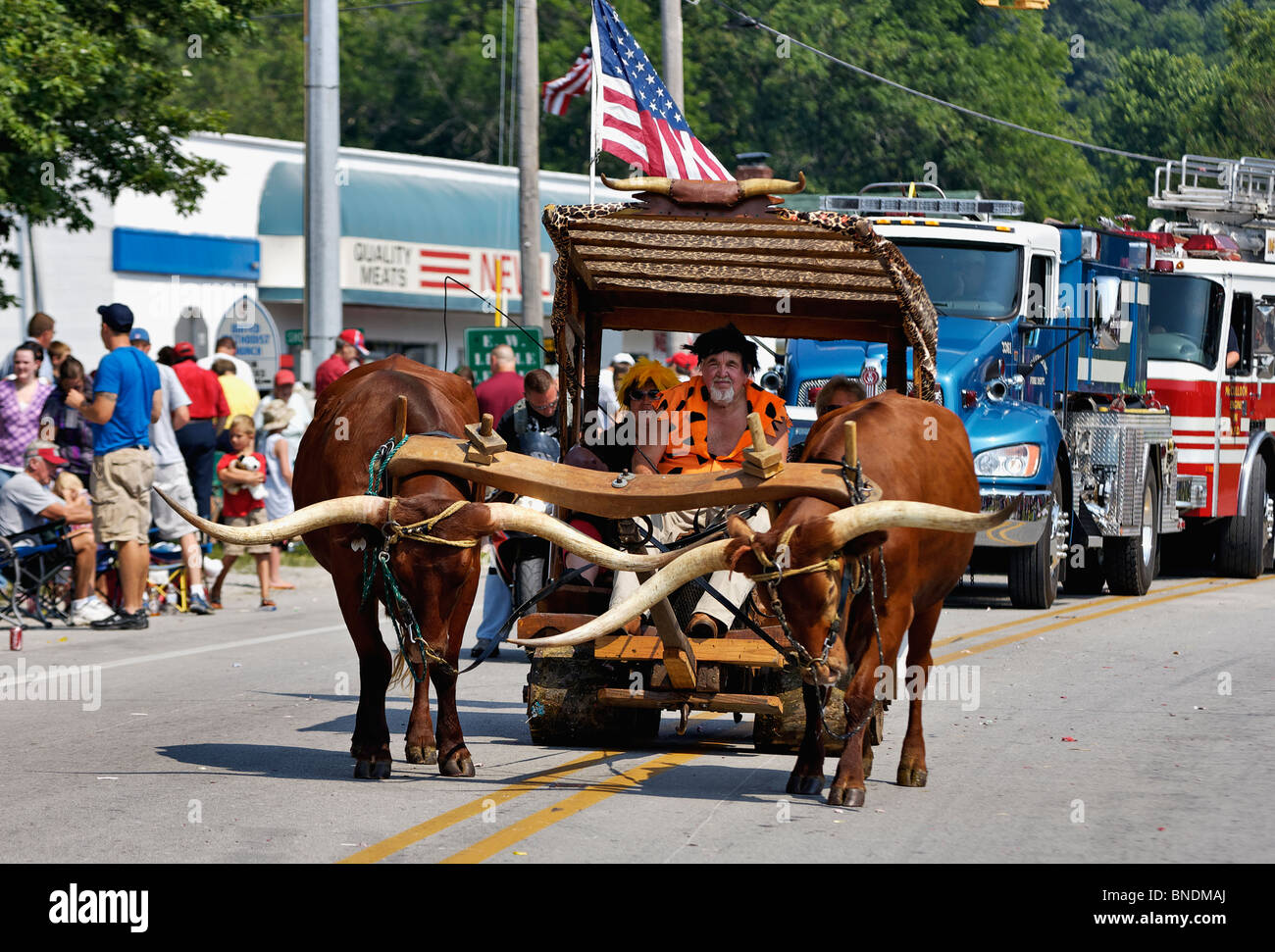 Homme habillé comme Fred Flintstone conduire boeufs dans plus ancienne Indépendance Day Parade en Amérique à New Pekin, Indiana Banque D'Images