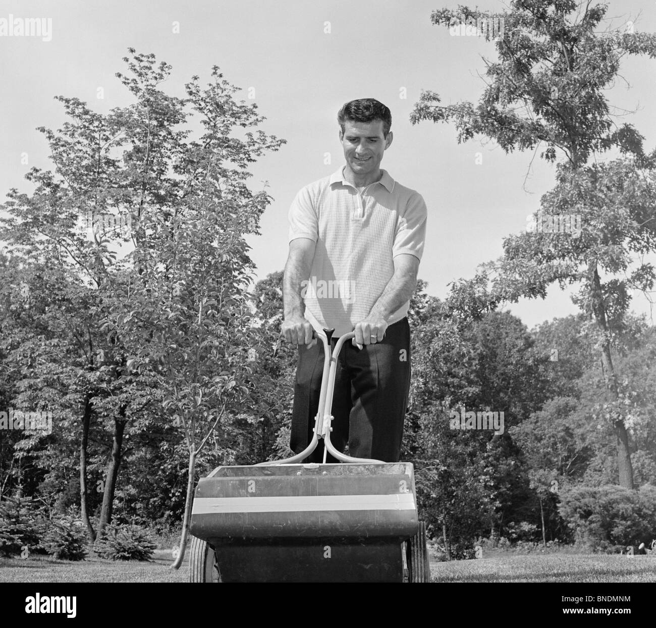 Low angle view of a young man fertiliser une pelouse Banque D'Images