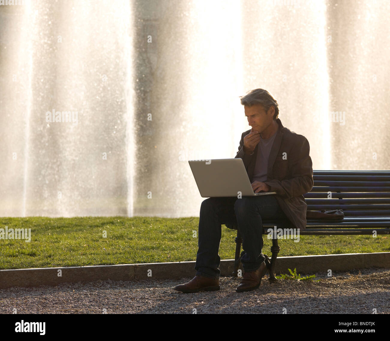 Businessman working on a laptop in a park Banque D'Images