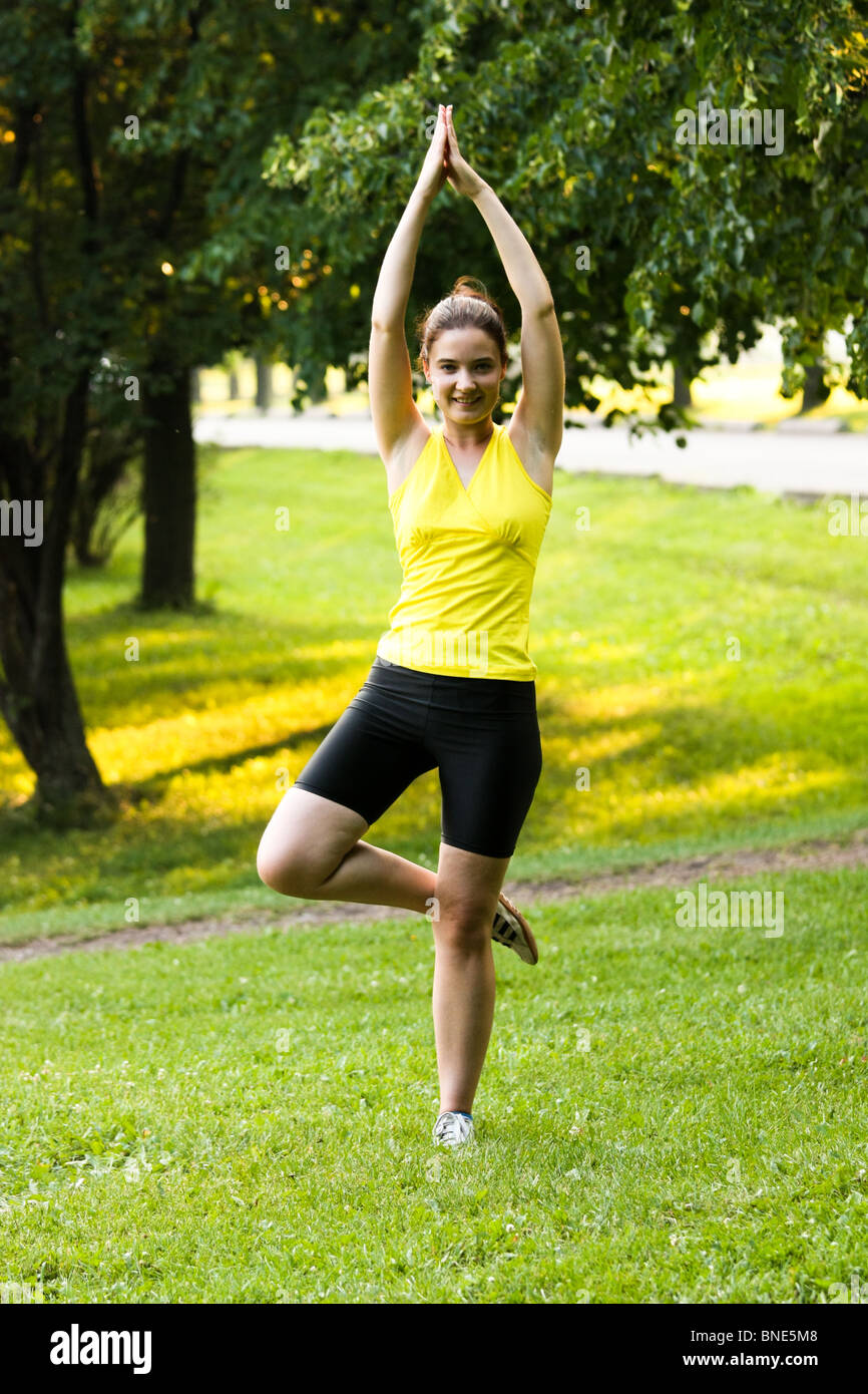 Jeune femme bras jambe stretching piscine soir Banque D'Images