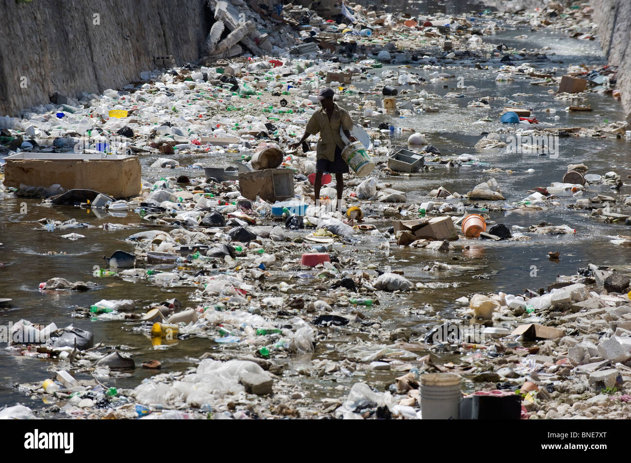 L'homme à une poubelle rempli Rivière, Port au Prince, Haïti, Caraïbes Banque D'Images