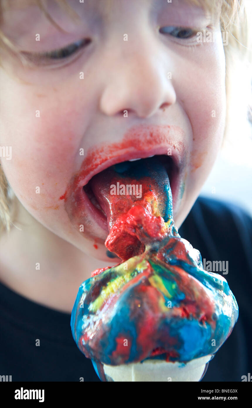 Jeune garçon savourant une glace aromatisée avec des agents de coloration malsaine Banque D'Images