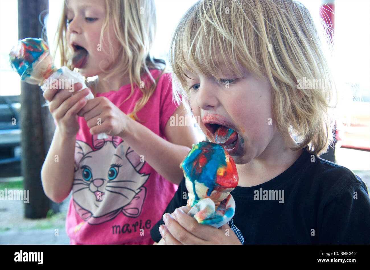 Les jeunes enfants de manger des glaces multicolores avec beaucoup d'agents de coloration, USA Banque D'Images