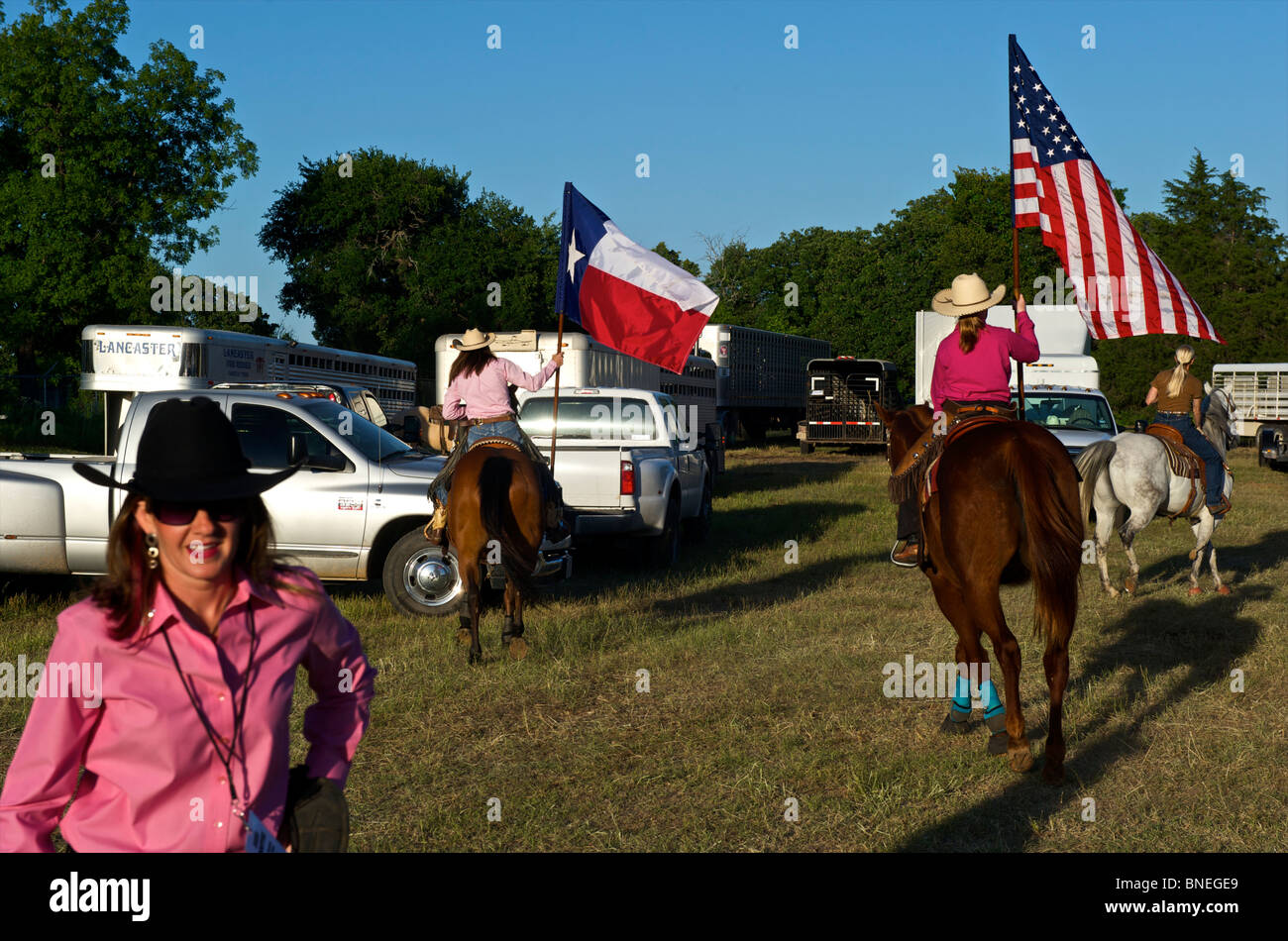 Cowgirls waving flag en bestiaux sur la cérémonie d'ouverture de l'érythroblastopénie événement rodéo au Texas, USA Banque D'Images