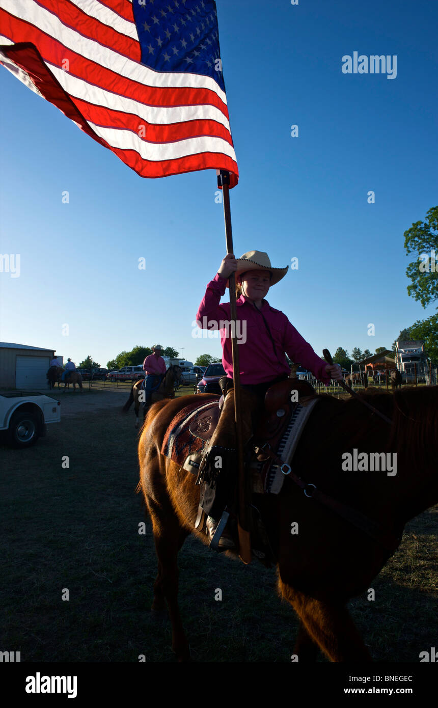 Cowgirl en agitant le drapeau américain à la cérémonie d'ouverture de l'érythroblastopénie événement rodéo au Texas, USA Banque D'Images