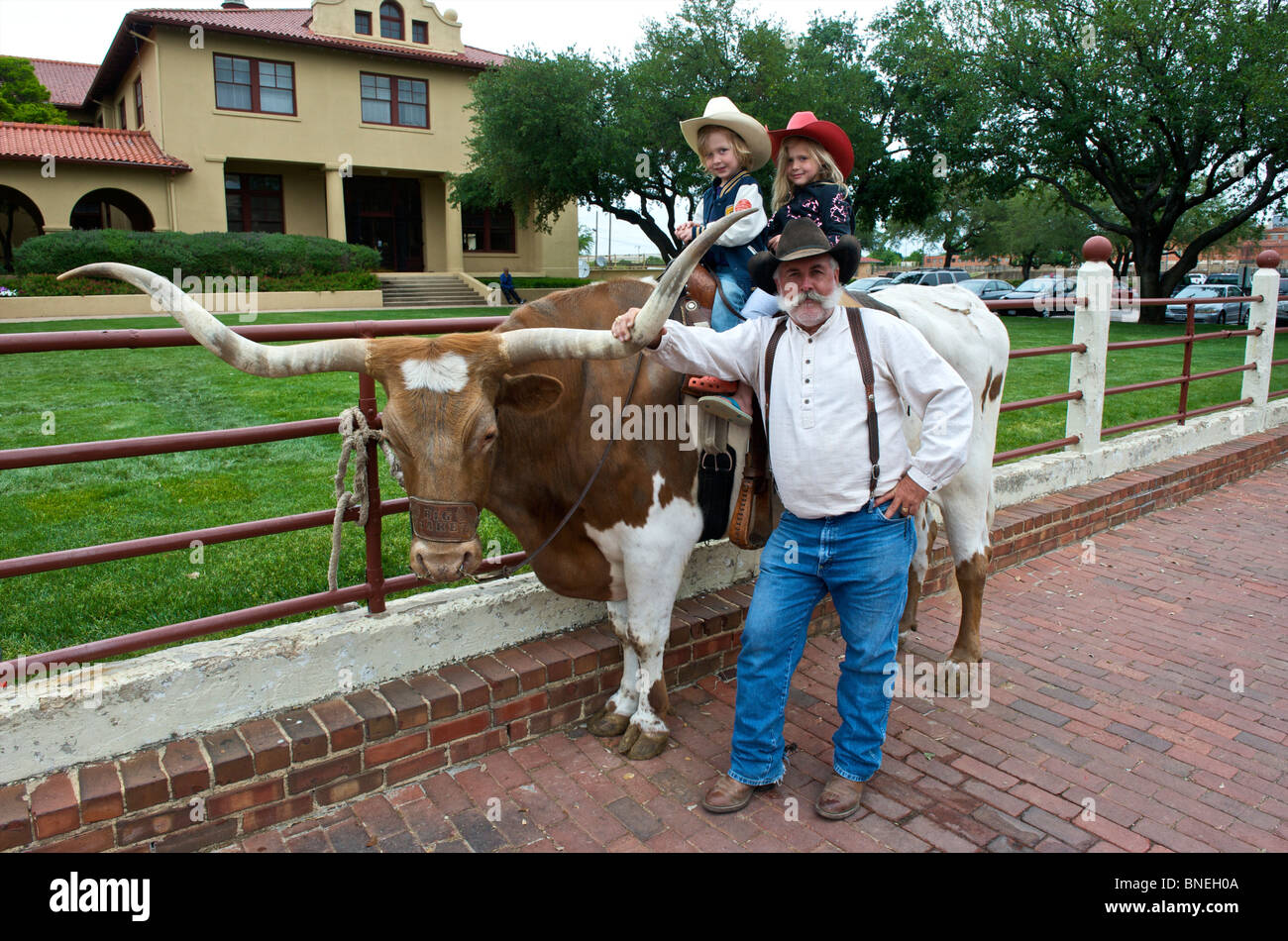 Enfants sur longhorns posant avec grand-père dans la région de Fort Worth, Texas, États-Unis Banque D'Images