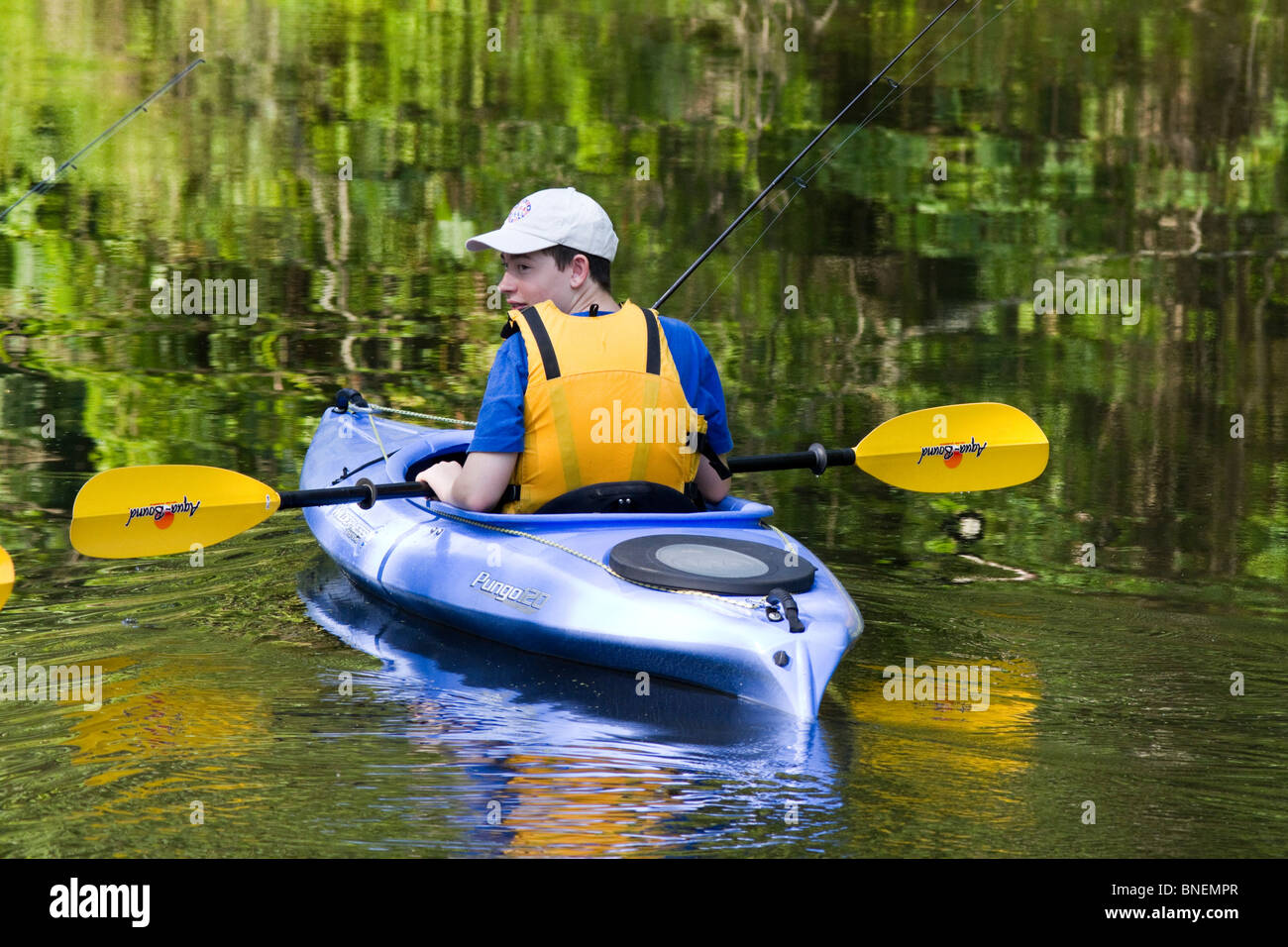 Un jeune garçon de race blanche dans un kayak avec gilet et les engins de pêche. Banque D'Images