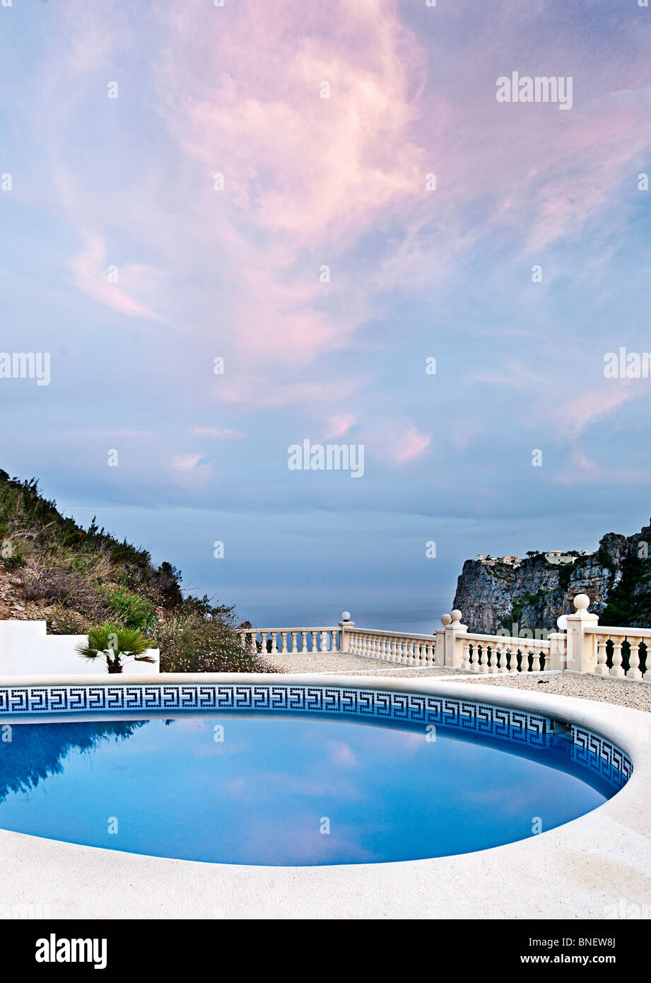 Beaux nuages roses sur une piscine de luxe sur la Costa Blanca, littoral de l'Espagne. Cumbre Del Sol, Benitachell Banque D'Images