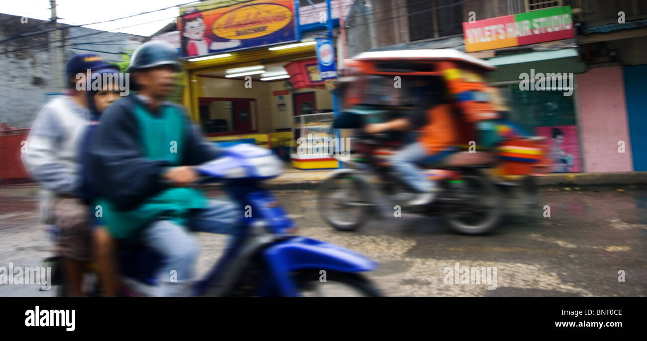 Tricycle et une moto sur une rue animée, Tagbilaran, Bohol, Philippines Banque D'Images
