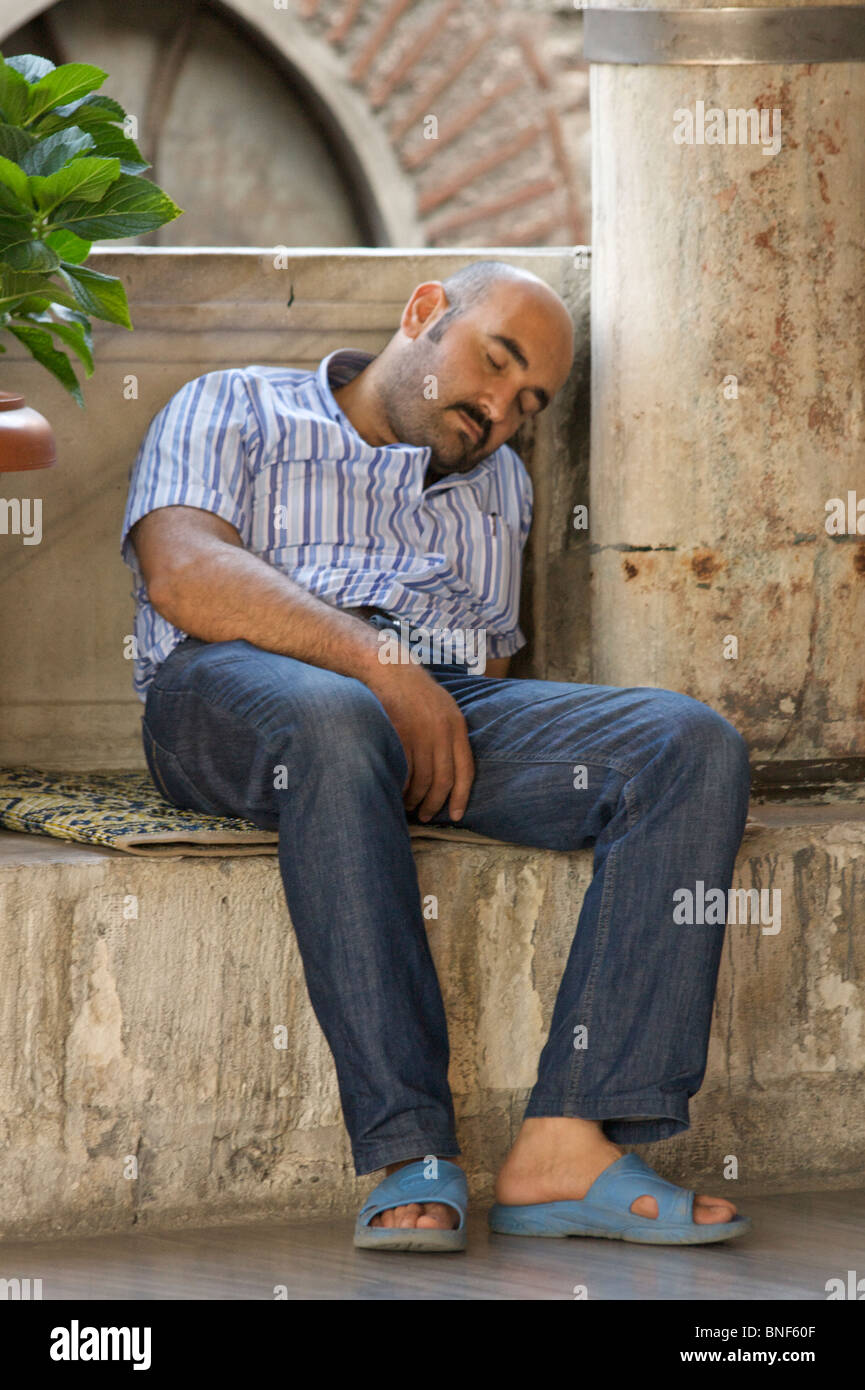 Le gardien de la mosquée Rustem Pacha en jeans bleu et des tongs, dormir  pendant une pause de la prière à l'extérieur de la mosquée Photo Stock -  Alamy