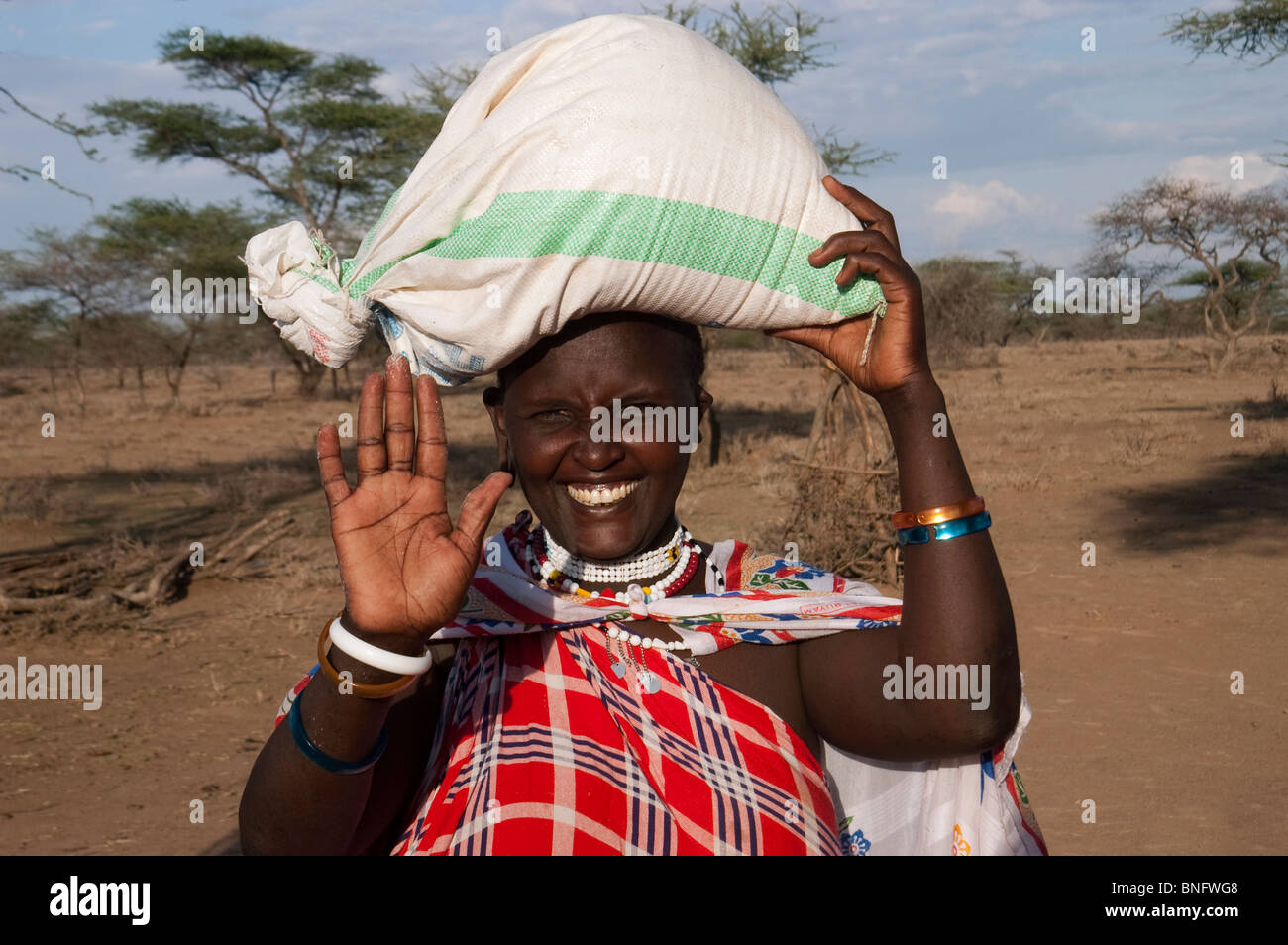 Accueil femme Masai en transportant un sac de maïs sur la tête, Malambo, région d'Arusha, Tanzanie Banque D'Images