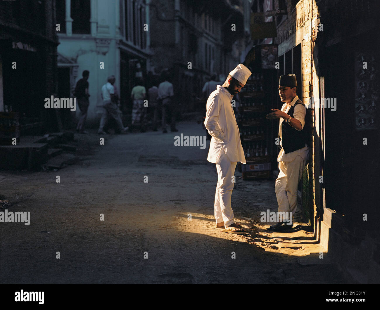 Deux hommes discuter dans une parcelle de la lumière du soleil dans une rue de Katmandou, Katmandou, Népal Banque D'Images