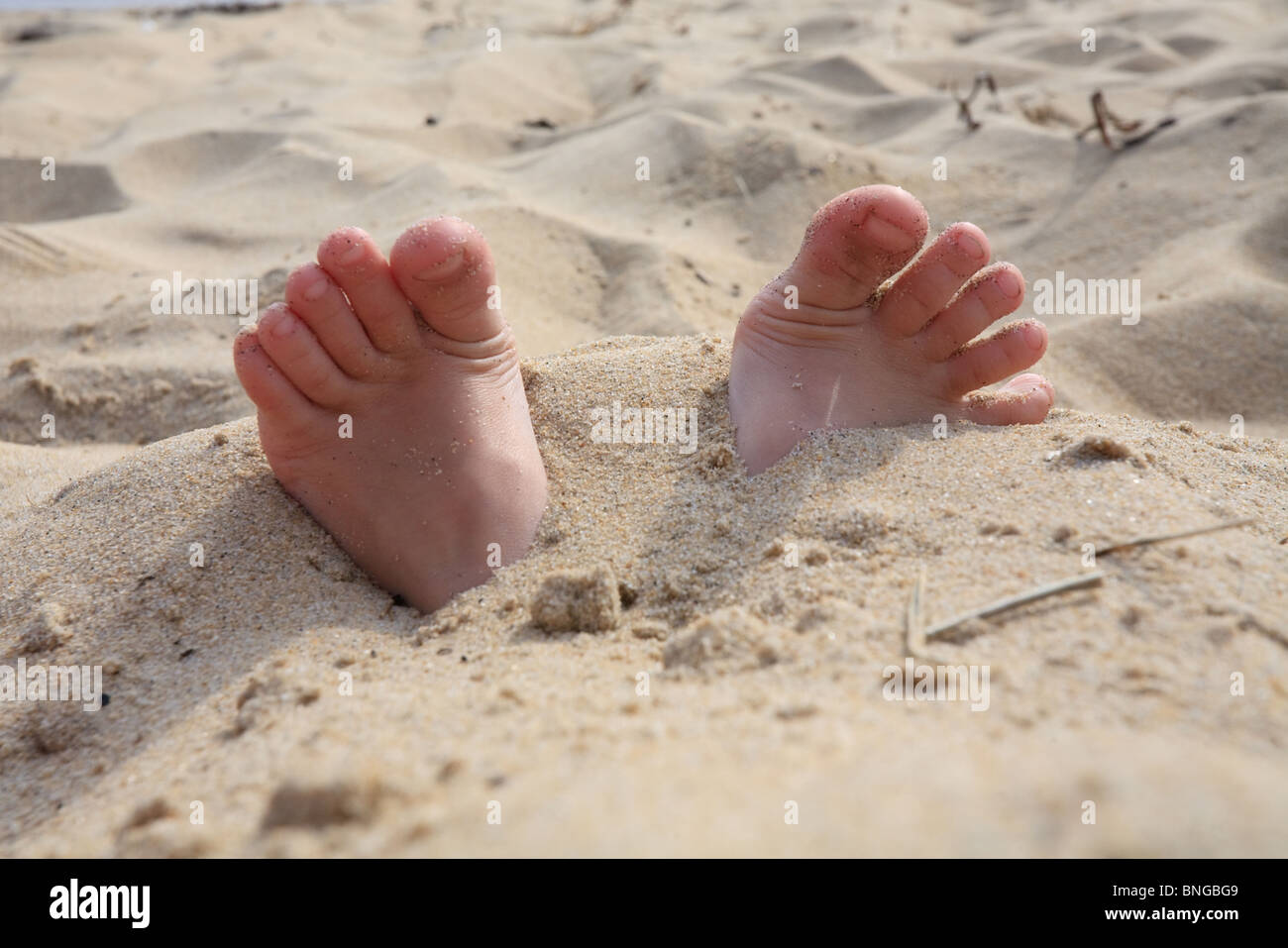 Les pieds des enfants sont enterrés dans le sable Banque D'Images