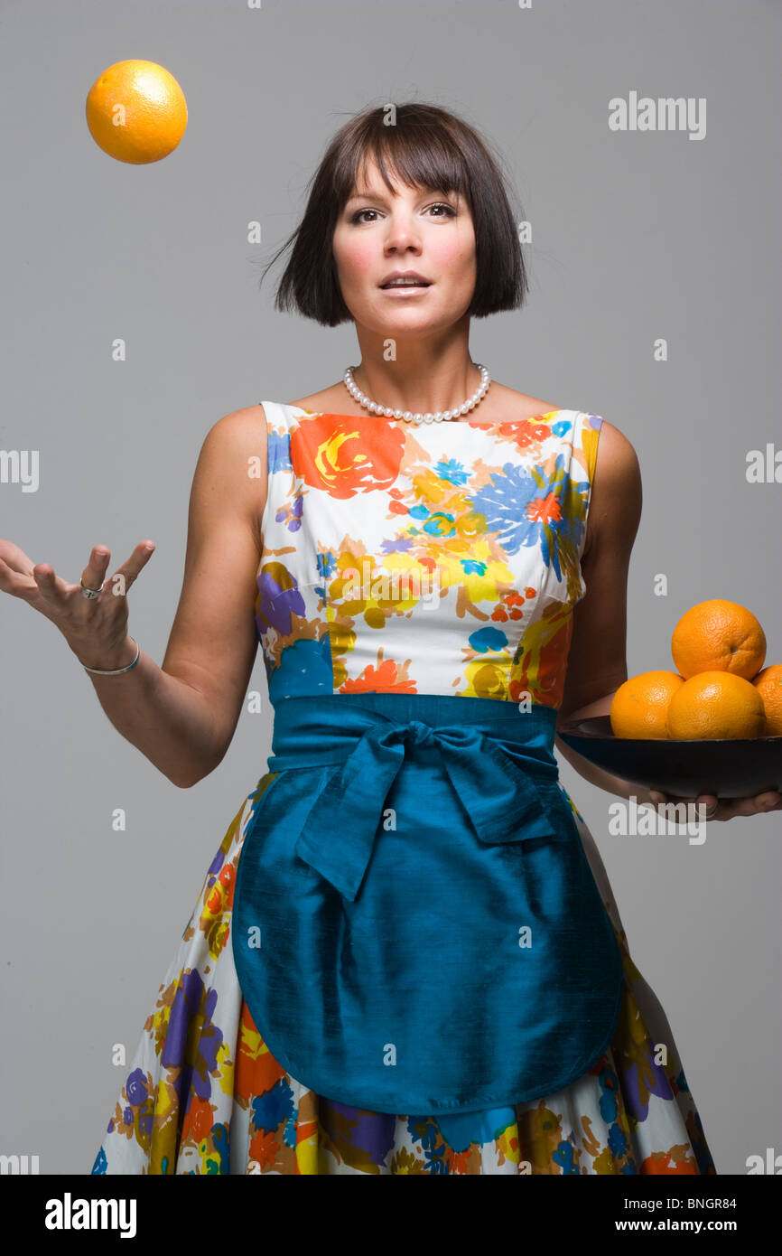 Portrait de studio de style des années 1950 woman tossing orange Banque D'Images