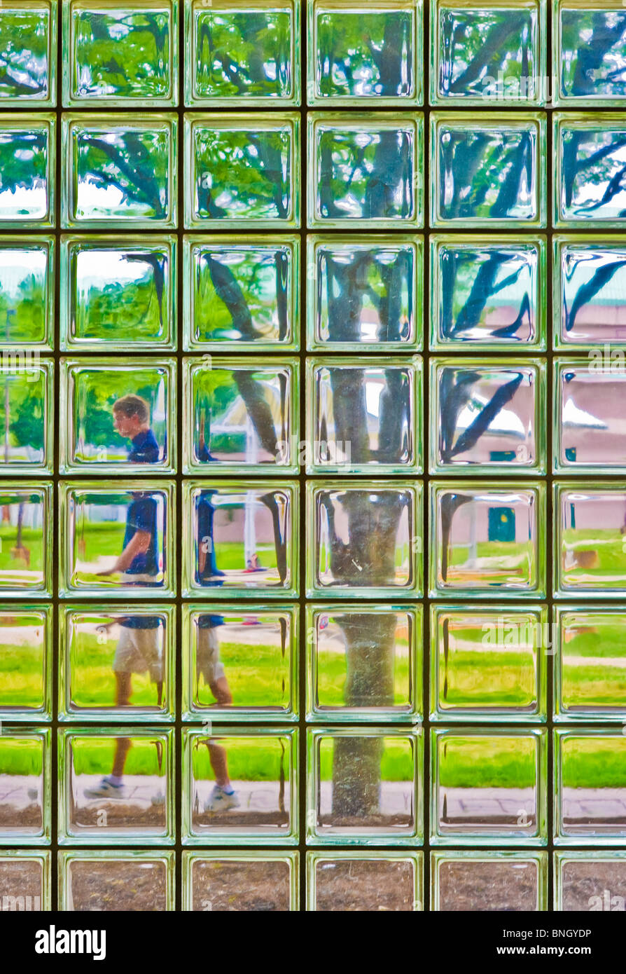 Personne marchant passé windows cour bloc de verre Banque D'Images