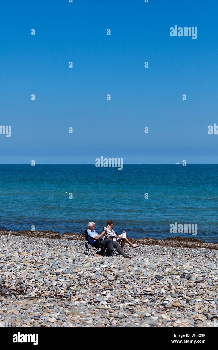 Couple de lire les journaux sur plage déserte à l'été à Bray, près de Dublin, Irlande Banque D'Images