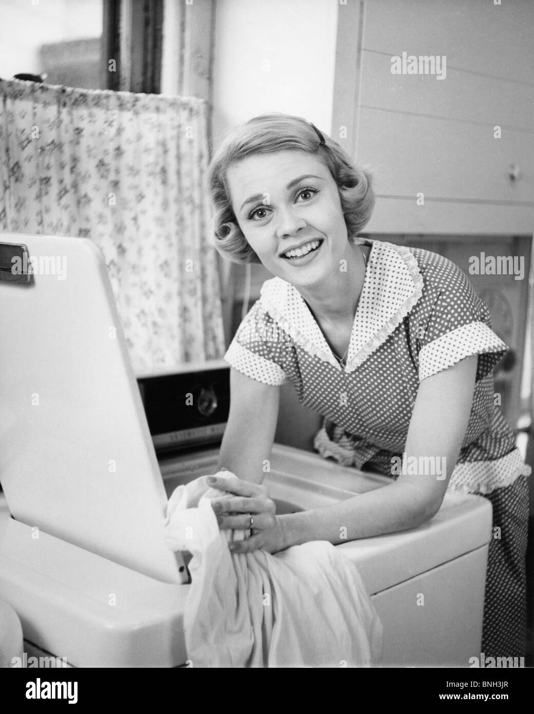 Portrait of young woman leaning on lave-linge Banque D'Images