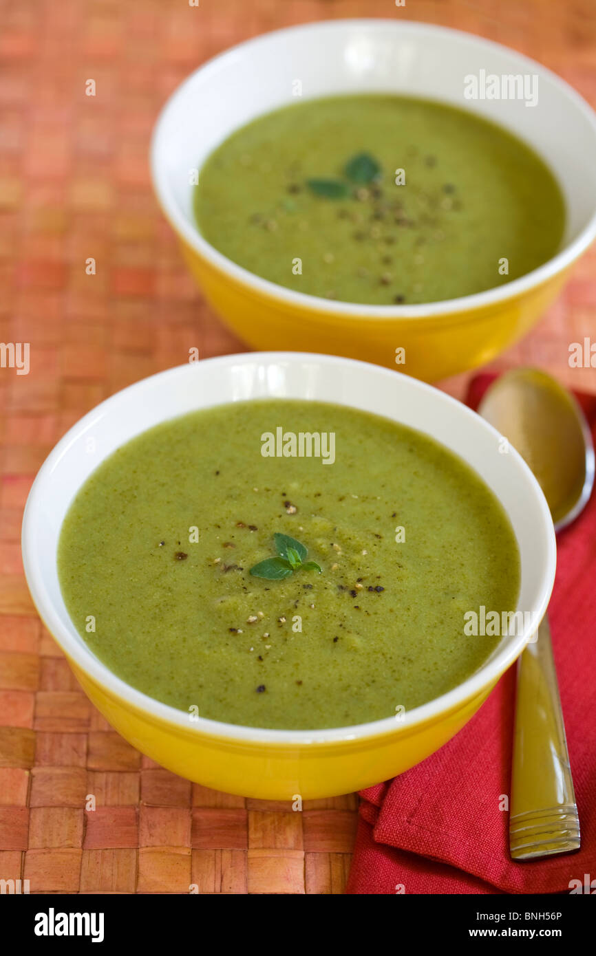 Soupe de brocoli dans deux bols jaune avec du poivre et des herbes Banque D'Images