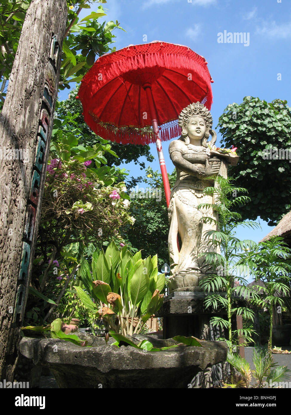 Asie Indonésie Bali statue de voyage parapluie rouge parasol vert figure plantes nature Banque D'Images