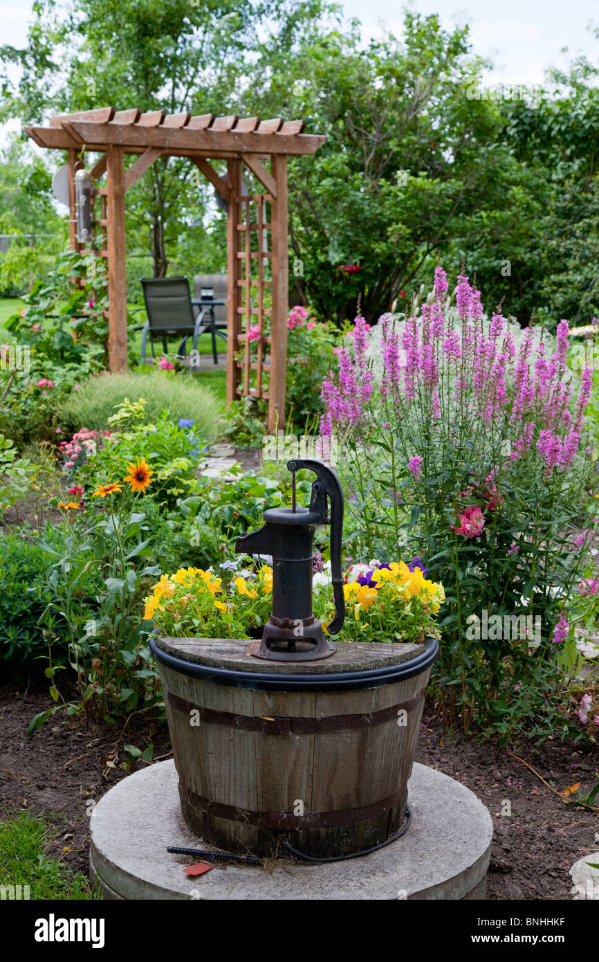 Une vieille pompe à eau décoratif dans le jardin avec des fleurs à Reinland, Manitoba, Canada. Banque D'Images
