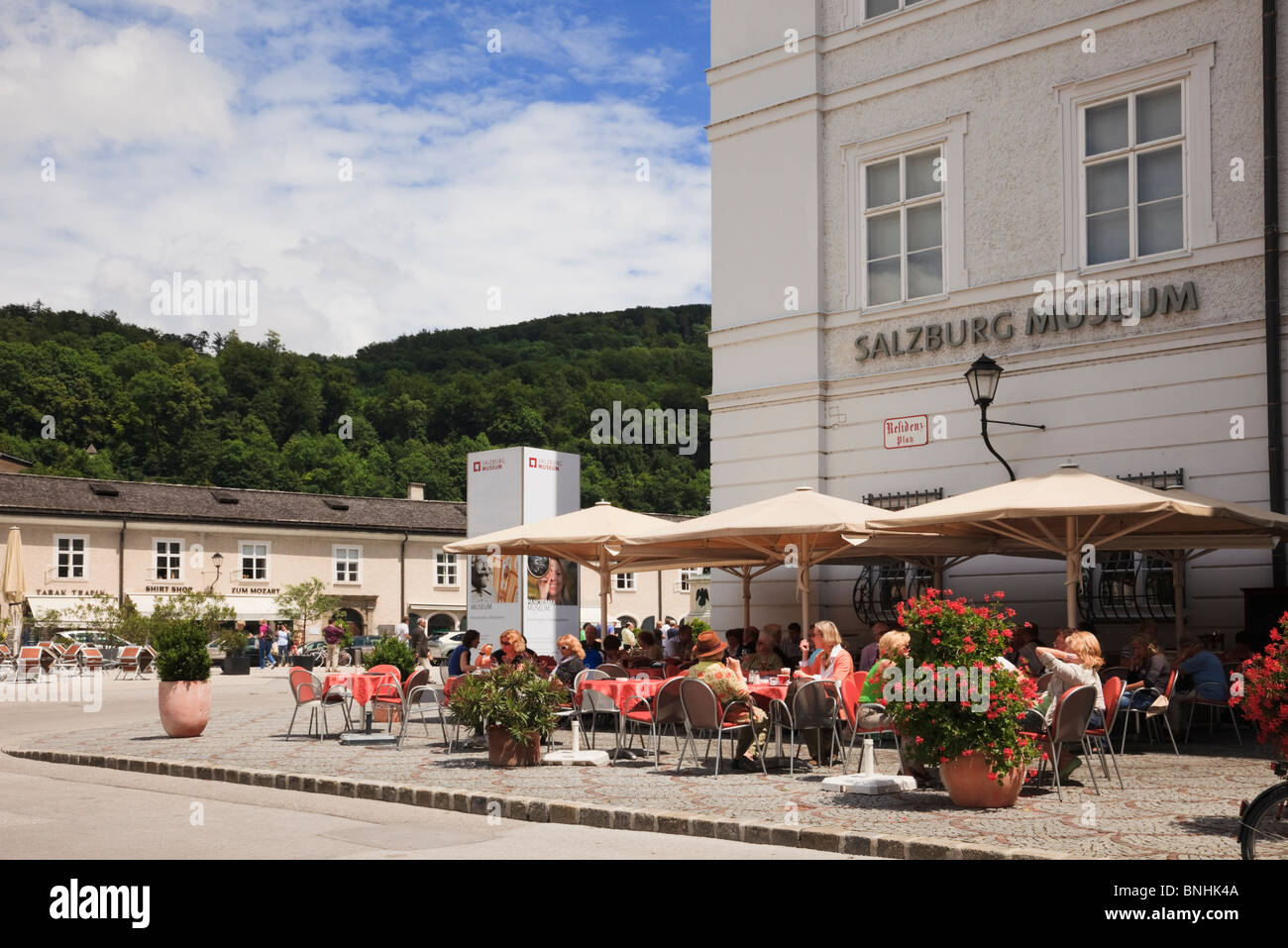 , Residenzplatz Salzbourg, Autriche. Les gens de manger à l'extérieur de Salzbourg Museum cafe de la chaussée avec statue au-delà Banque D'Images