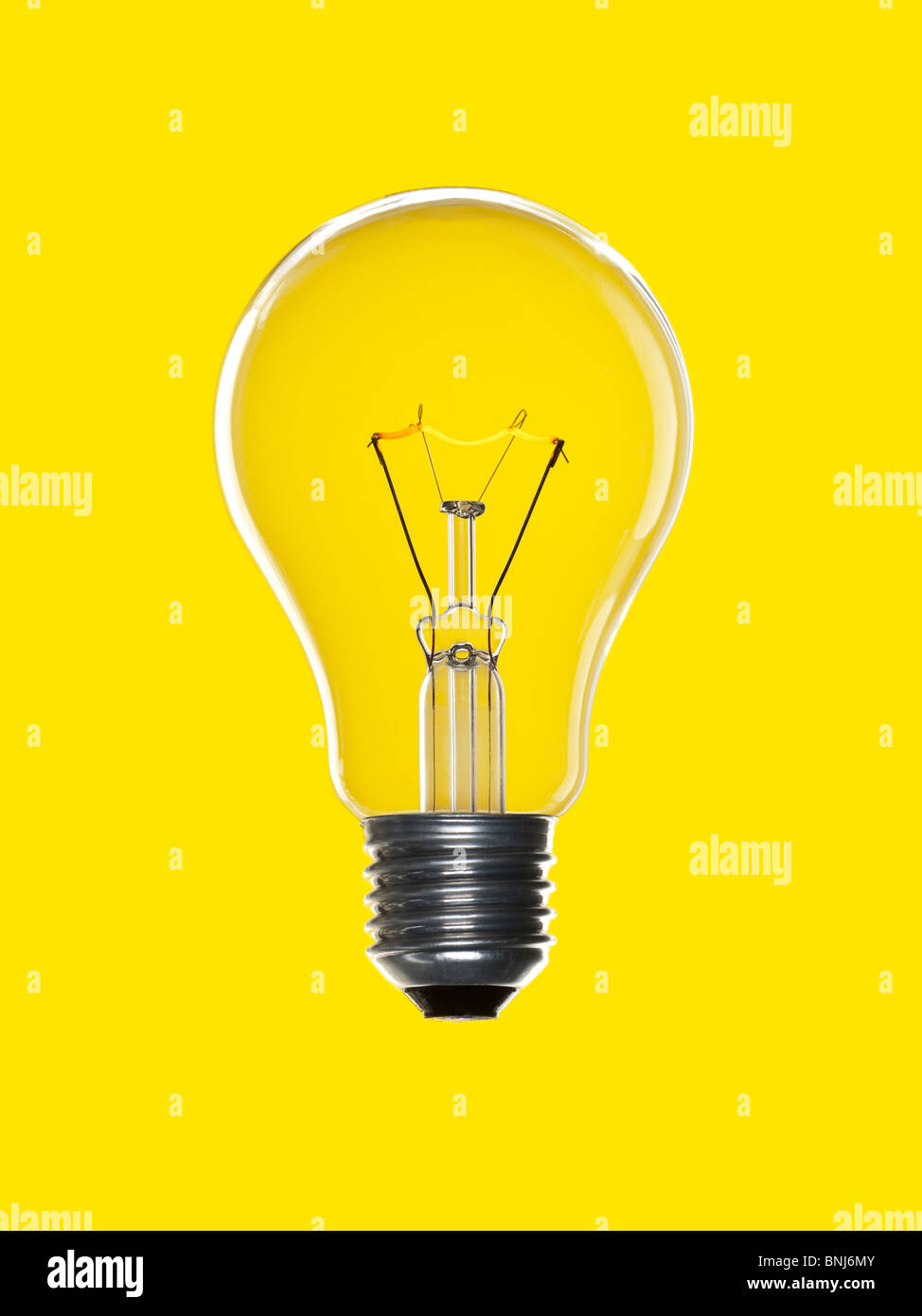 Une ampoule sur un fond jaune. Le tungstène du filament incandescent. Banque D'Images