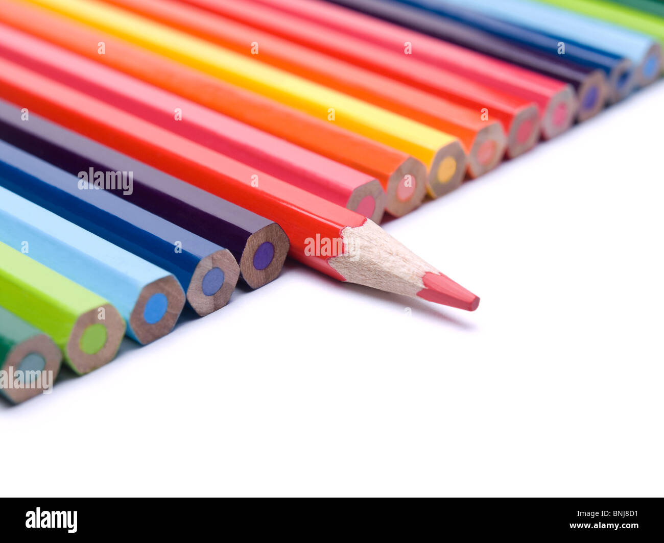 Un crayon rouge sort de la rangée de crayons de couleur. Banque D'Images