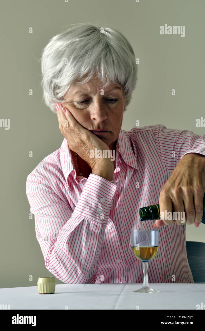 L'alcool triste Sherry Mature Senior Woman Ancienne Deprissed pensionné seul malade Malheureux Seul à seul verre de liqueur Banque D'Images